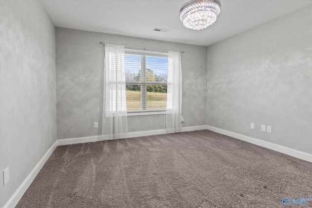 carpeted spare room with visible vents, baseboards, and an inviting chandelier