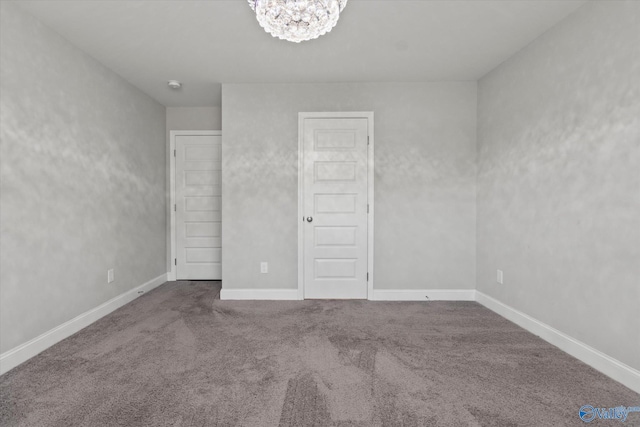 unfurnished bedroom featuring baseboards, carpet flooring, and a chandelier