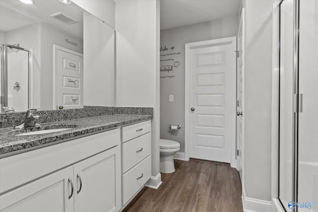full bathroom featuring a shower stall, wood finished floors, visible vents, toilet, and vanity