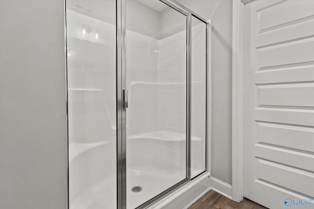 full bathroom featuring a shower stall, baseboards, and wood finished floors