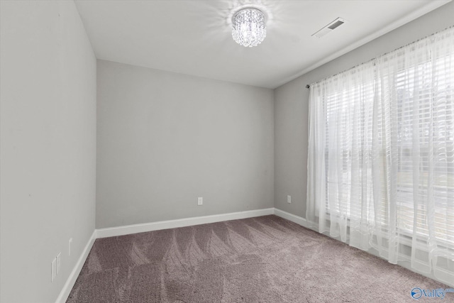carpeted spare room featuring an inviting chandelier, visible vents, and baseboards
