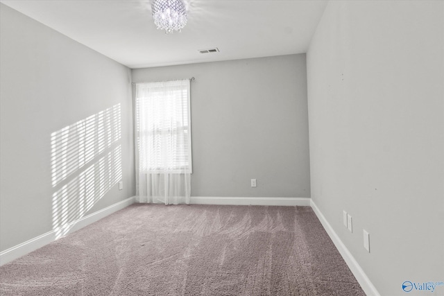 empty room featuring baseboards, visible vents, carpet, and a notable chandelier