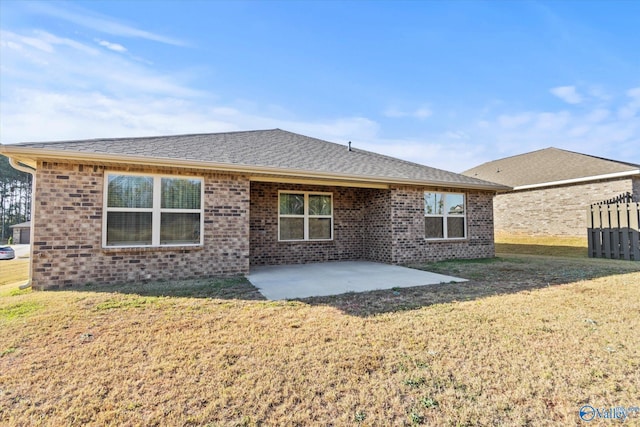 back of property with a lawn, a shingled roof, brick siding, and a patio