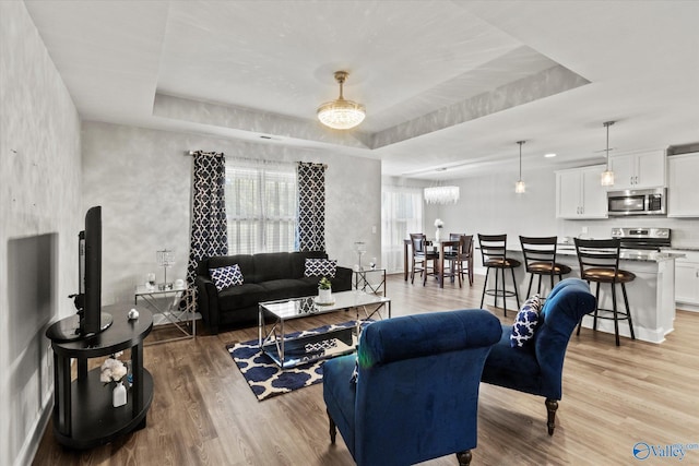 living area featuring a tray ceiling and light wood-type flooring
