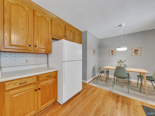 1011 Cole Dr SE, Huntsville, AL 35802 - kitchen featuring freestanding refrigerator, light wood-style flooring, light countertops, tasteful backsplash, and decorative light fixtures