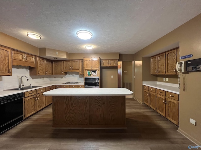 kitchen featuring brown cabinets, a sink, black dishwasher, stainless steel gas stovetop, and a kitchen island
