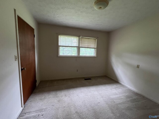 carpeted empty room featuring a textured ceiling and baseboards