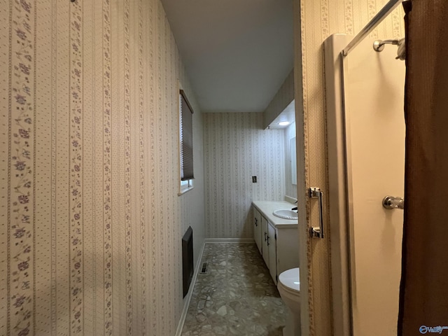 bathroom featuring wallpapered walls, toilet, baseboards, and vanity
