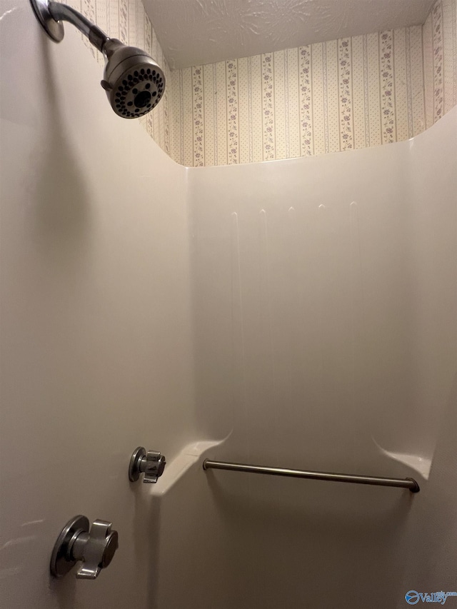 interior details with a textured ceiling and a shower