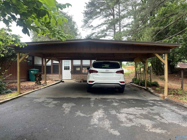 view of parking / parking lot with a carport, fence, and aphalt driveway