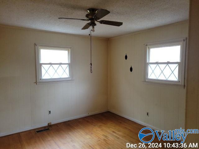 unfurnished room featuring a wealth of natural light, light hardwood / wood-style flooring, and a textured ceiling