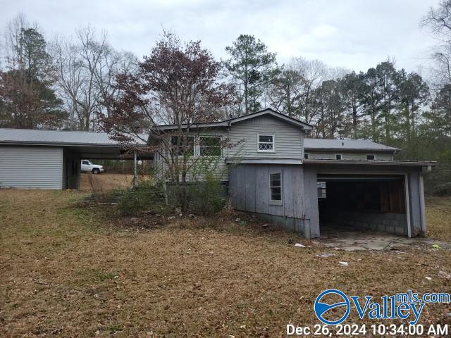 rear view of property with a garage and a carport