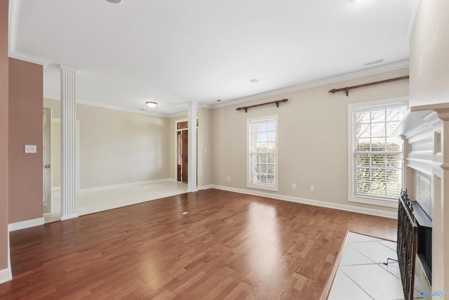 unfurnished living room featuring ornamental molding, a high end fireplace, wood-type flooring, and ornate columns