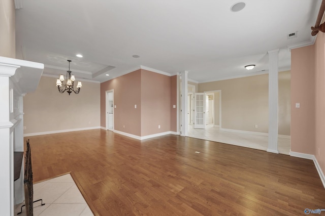 unfurnished living room with hardwood / wood-style floors, crown molding, a raised ceiling, and ornate columns