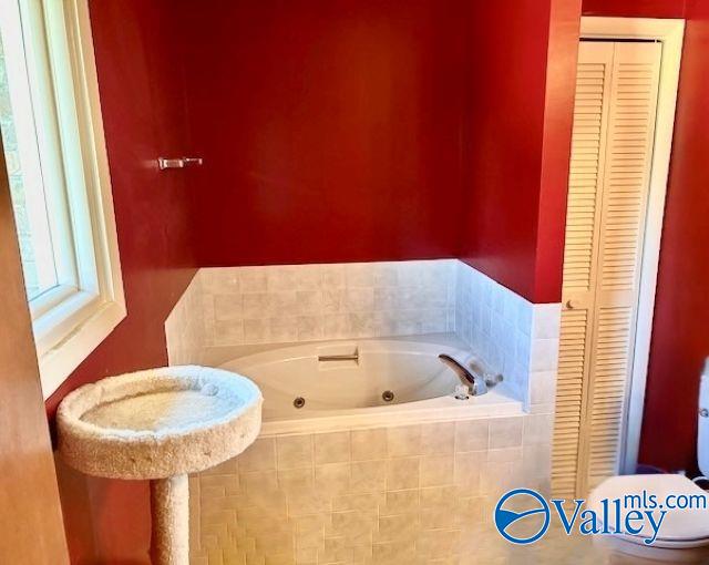 bathroom featuring tiled bath and toilet