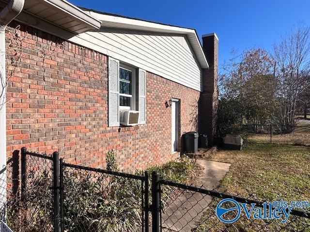 view of home's exterior with brick siding, cooling unit, and fence