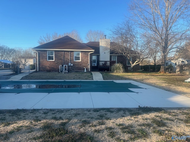 view of front of home with a wooden deck, a front yard, a chimney, and brick siding