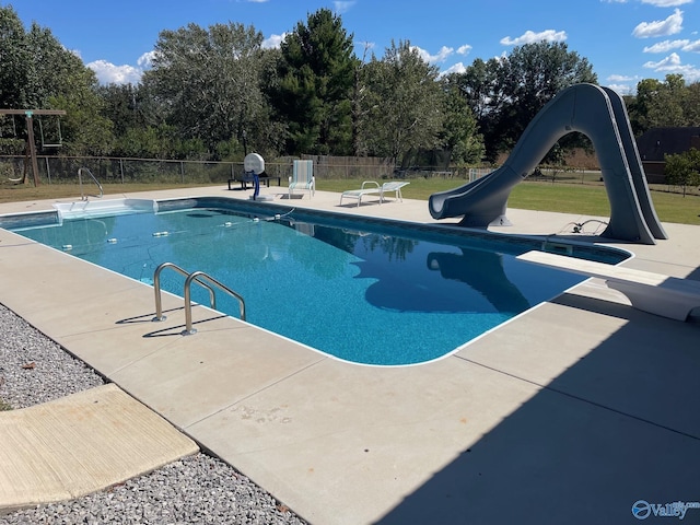 view of pool with a lawn, a fenced in pool, fence, a water slide, and a patio area