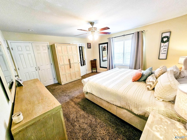 bedroom with ceiling fan, dark carpet, a textured ceiling, and two closets