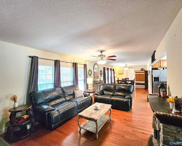 living room featuring hardwood / wood-style flooring, a textured ceiling, and ceiling fan