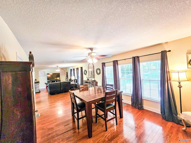 dining space featuring a textured ceiling, wood-type flooring, and ceiling fan