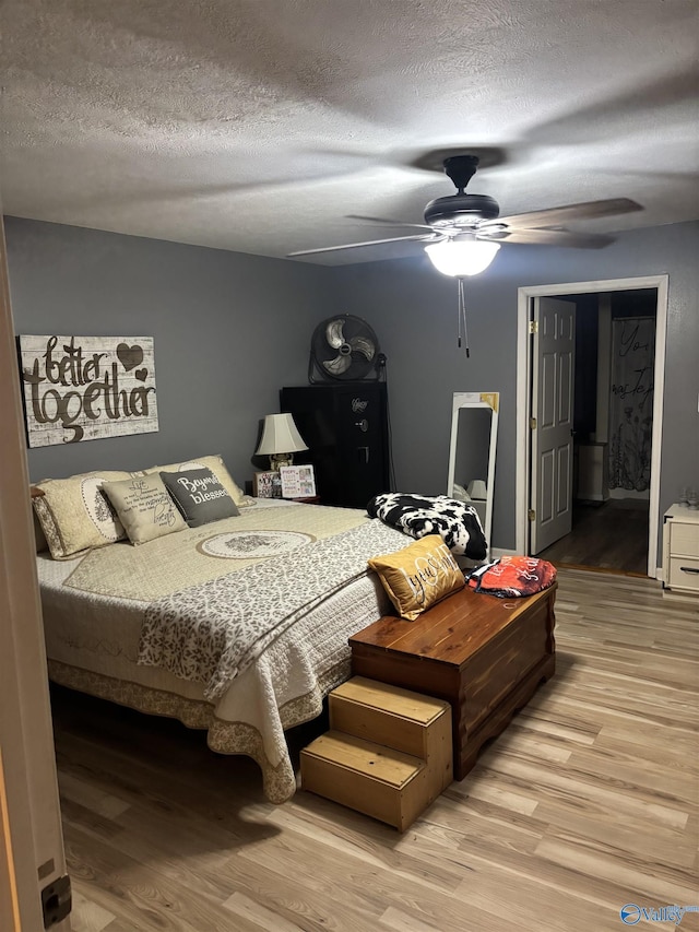 bedroom with ceiling fan, wood-type flooring, and a textured ceiling