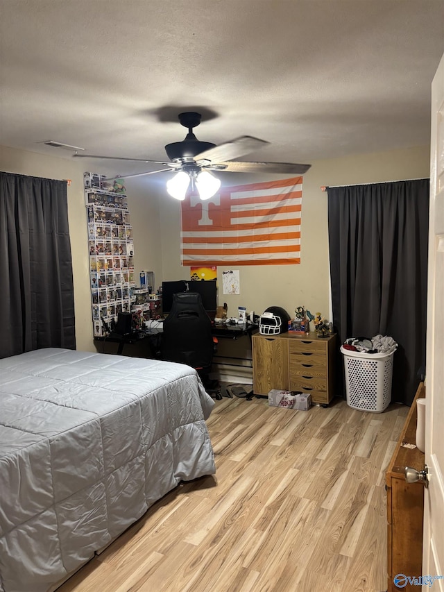 bedroom featuring ceiling fan, hardwood / wood-style floors, and a textured ceiling