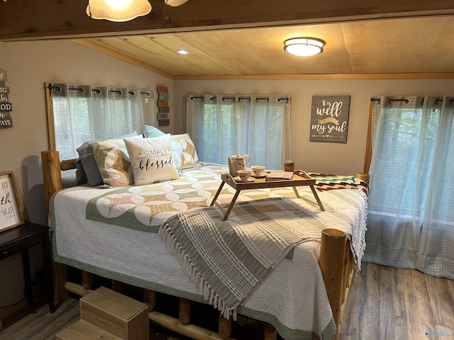 bedroom featuring lofted ceiling with beams, hardwood / wood-style floors, and multiple windows