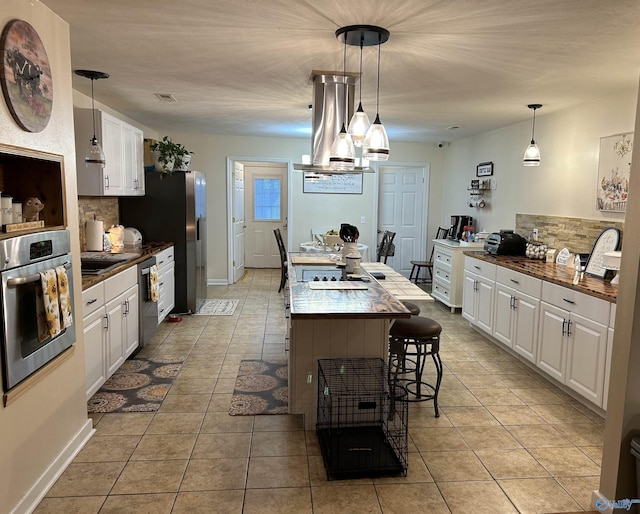 kitchen featuring stainless steel appliances, white cabinetry, and pendant lighting