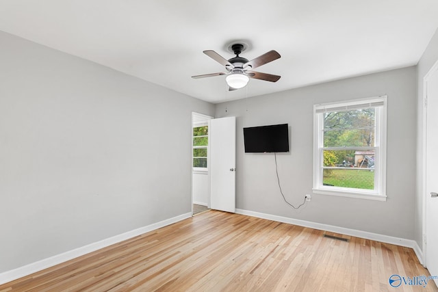 empty room featuring ceiling fan, plenty of natural light, and light hardwood / wood-style flooring