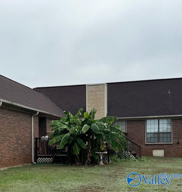 exterior space with brick siding and a lawn