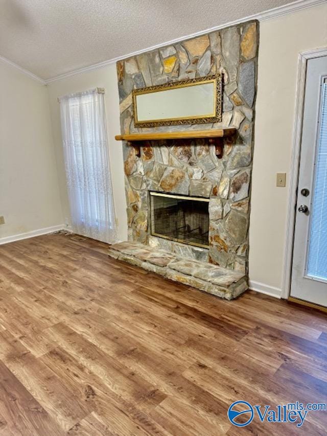 unfurnished living room featuring a fireplace, crown molding, a textured ceiling, and wood finished floors