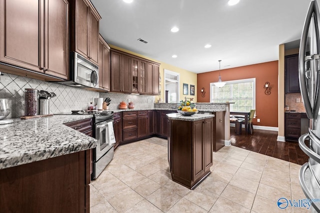 126 Mattie Ct, Madison, AL 35756 - kitchen with appliances with stainless steel finishes, a peninsula, decorative backsplash, light stone counters, and recessed lighting