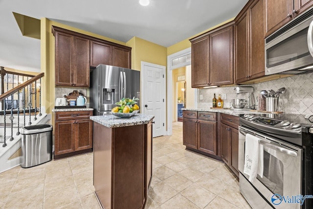 126 Mattie Ct, Madison, AL 35756 - kitchen featuring appliances with stainless steel finishes, light stone counters, tasteful backsplash, a center island, and light tile patterned floors