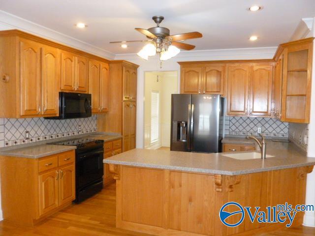 kitchen with light countertops, a peninsula, a sink, and black appliances