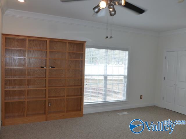 unfurnished bedroom with a closet, crown molding, carpet floors, a ceiling fan, and baseboards