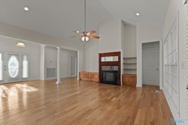 unfurnished living room featuring high vaulted ceiling, light wood-style floors, visible vents, a tiled fireplace, and a ceiling fan