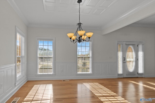 unfurnished dining area featuring ornamental molding, light wood-style floors, visible vents, a notable chandelier, and wainscoting