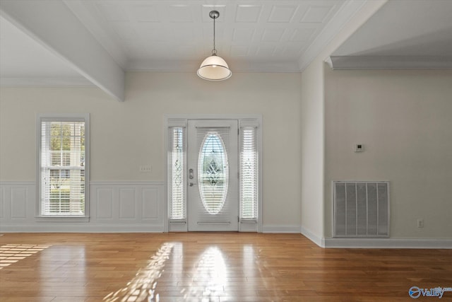 foyer entrance with a wainscoted wall, visible vents, crown molding, and wood finished floors
