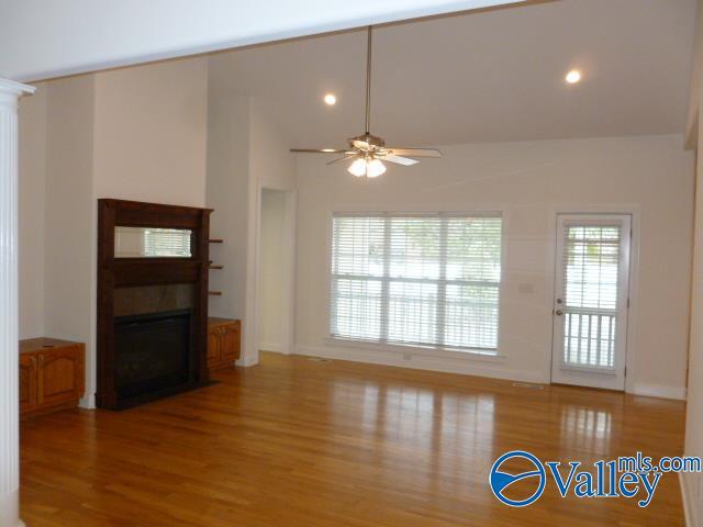 unfurnished living room with vaulted ceiling, recessed lighting, a fireplace with flush hearth, a ceiling fan, and wood finished floors