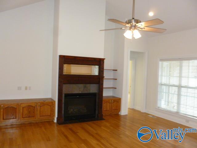 unfurnished living room featuring light wood finished floors, a fireplace with flush hearth, and ceiling fan