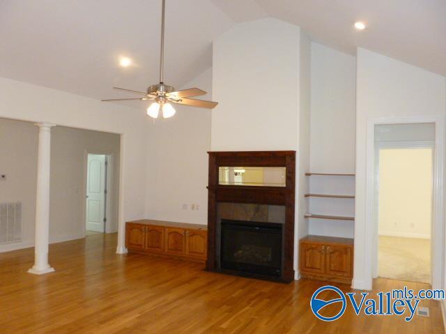 unfurnished living room featuring light wood-type flooring, high vaulted ceiling, ceiling fan, visible vents, and a fireplace