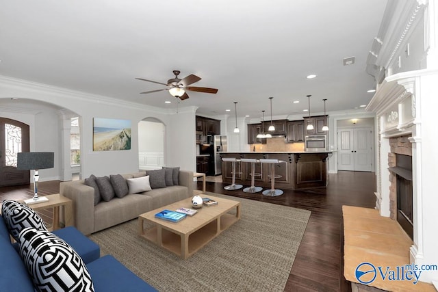 living room featuring dark wood-type flooring, ceiling fan, and ornamental molding