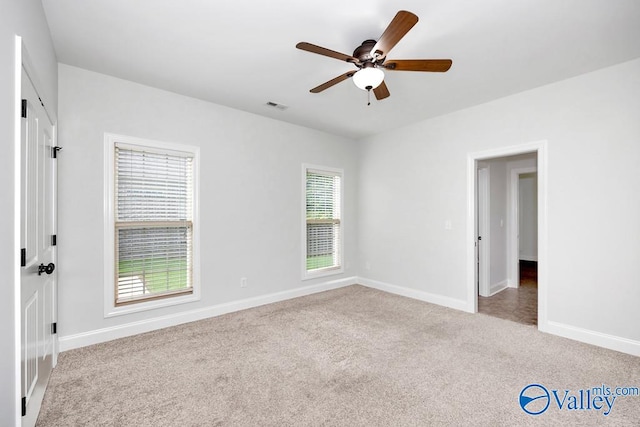 unfurnished room featuring a healthy amount of sunlight, light carpet, and ceiling fan