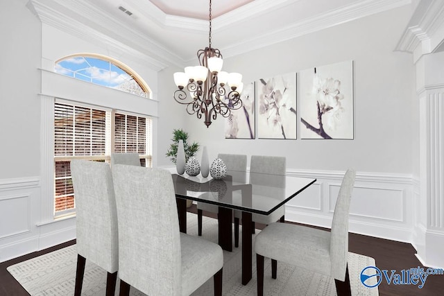 dining room with wood-type flooring, a notable chandelier, crown molding, and a raised ceiling