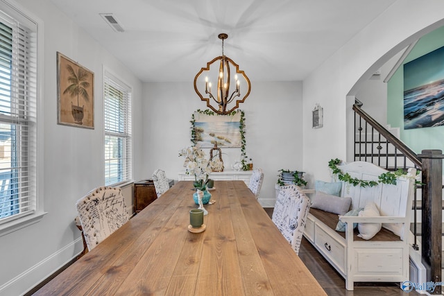 dining area featuring baseboards, visible vents, arched walkways, stairway, and a notable chandelier