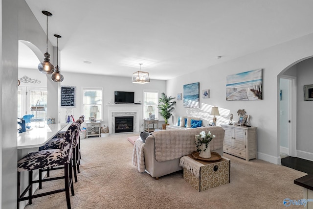 living area with carpet, a premium fireplace, arched walkways, and baseboards