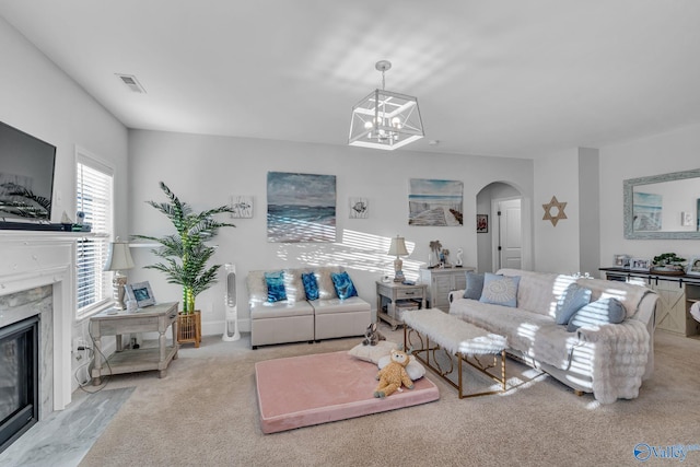 living room with arched walkways, a fireplace, a notable chandelier, visible vents, and light carpet