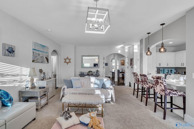 living area featuring arched walkways, light colored carpet, and an inviting chandelier