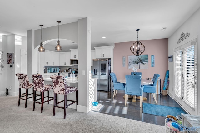 kitchen with a chandelier, stainless steel appliances, a kitchen breakfast bar, white cabinets, and light countertops